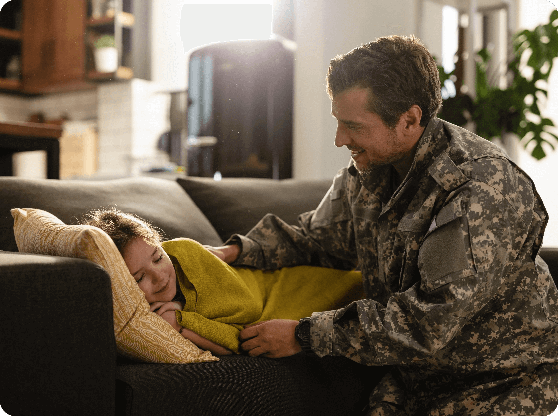 affectionate-soldier-looking-his-sleepy-daughter-who-is-lying-sofa-home@2x (1) (1)